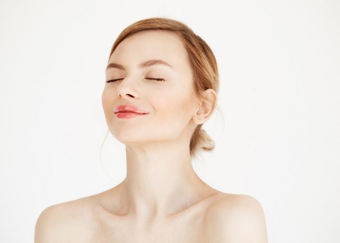 Portrait of young beautiful girl with clean fresh skin isolated on white background. Closed eyes. Beauty and health lifestyle. Copy space.